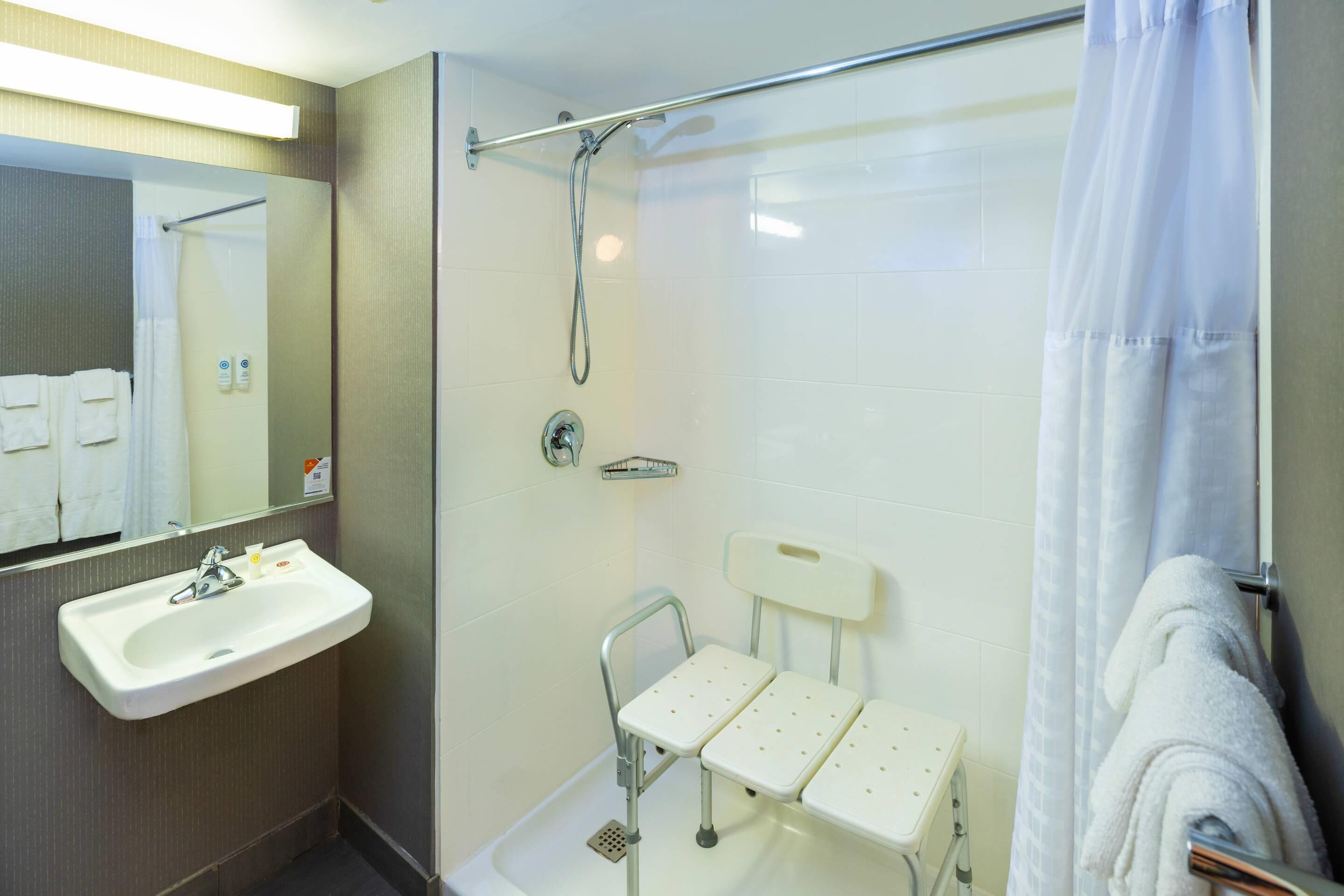 Une salle de bain avec une douche, un lavabo et un miroir.