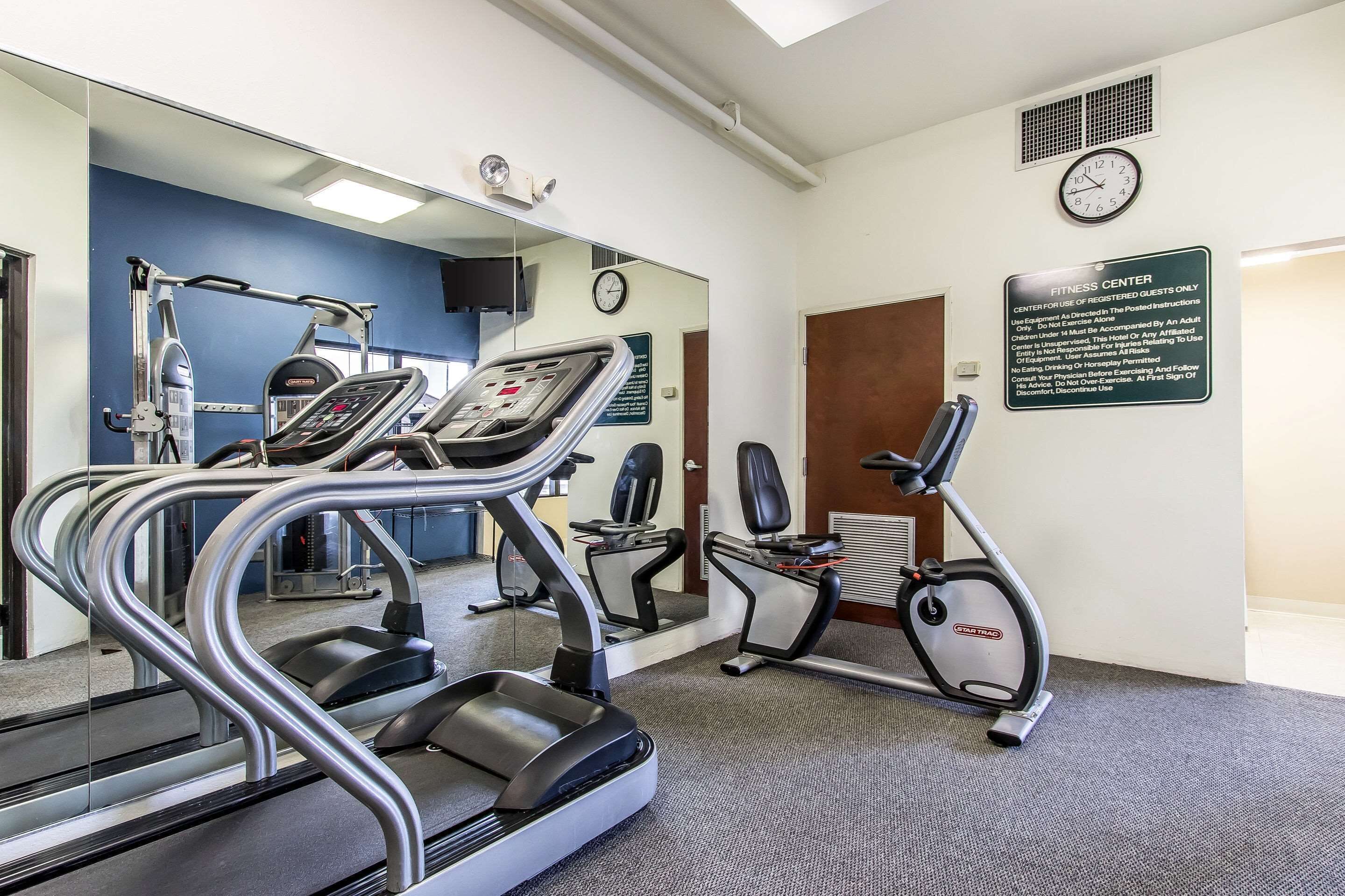 A fitness center with treadmills, elliptical machines, and a mirrored wall.