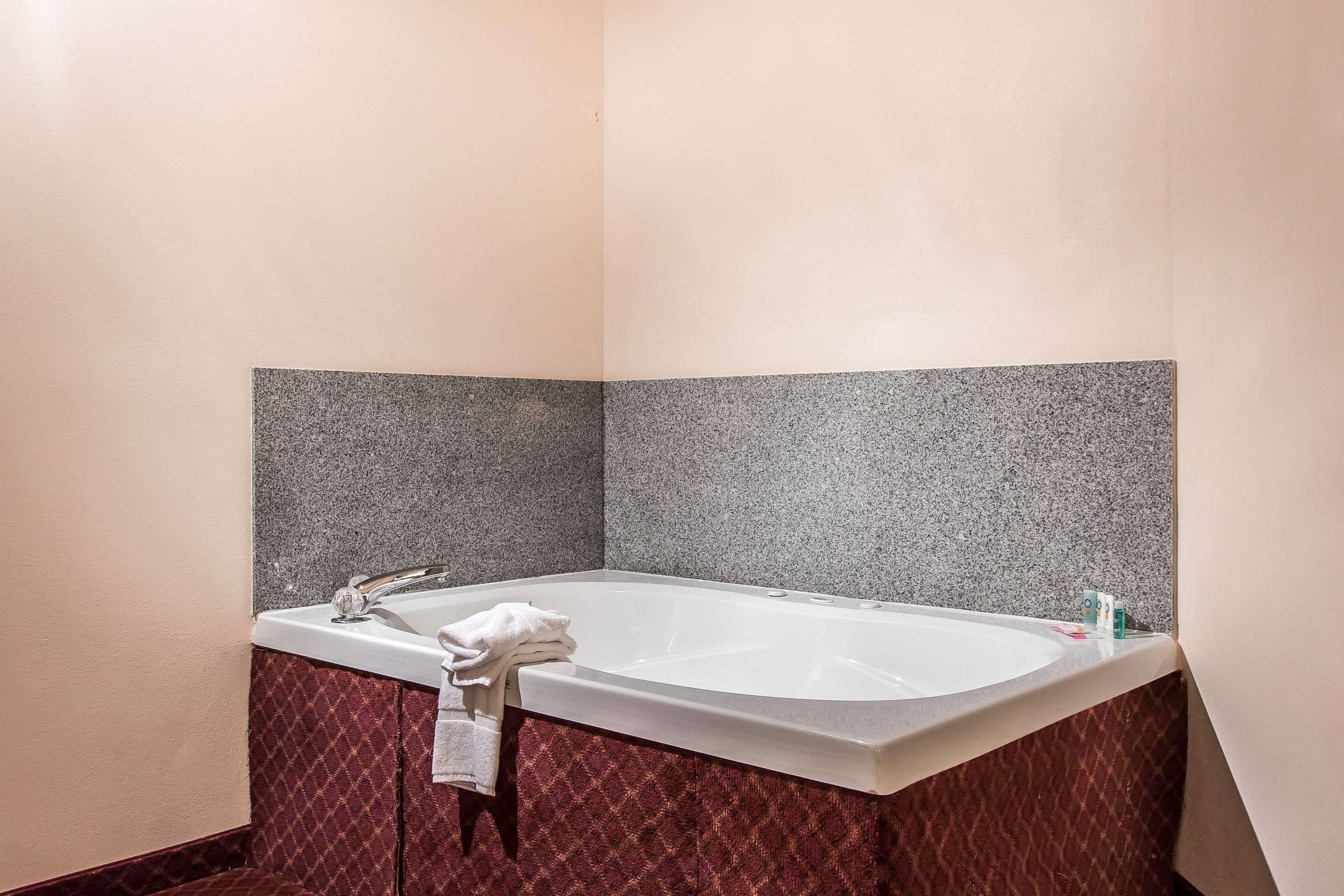 A bathroom with a freestanding bathtub, a towel rack, and a marble wall.