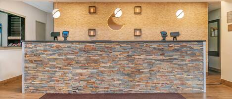 Un área de recepción con pared de piedra, suelo de madera y alfombra marrón.