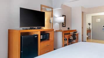 A hotel room with a bed, a desk with a chair, a television, a microwave, and a refrigerator.