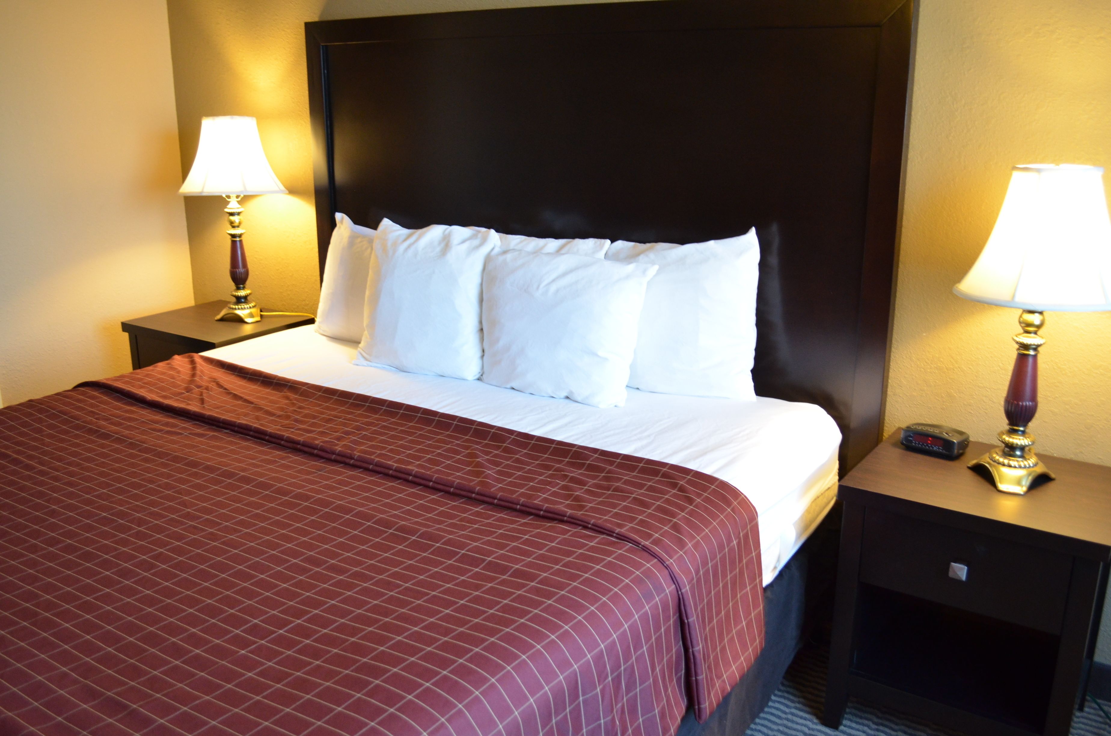 A hotel room with a large bed, two bedside tables, and lamps.
