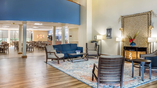 Un vestíbulo amplio con una pared azul decorativa, un tapete estampado y una zona de estar con sofá y sillones.