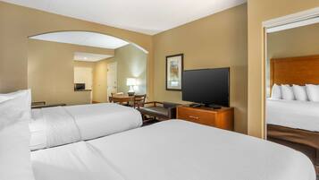 A hotel room with two beds, a desk with a chair, a television, and a mirror.