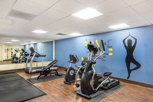 A gym with treadmills, stationary bikes, and a wall with fitness-related graphics.