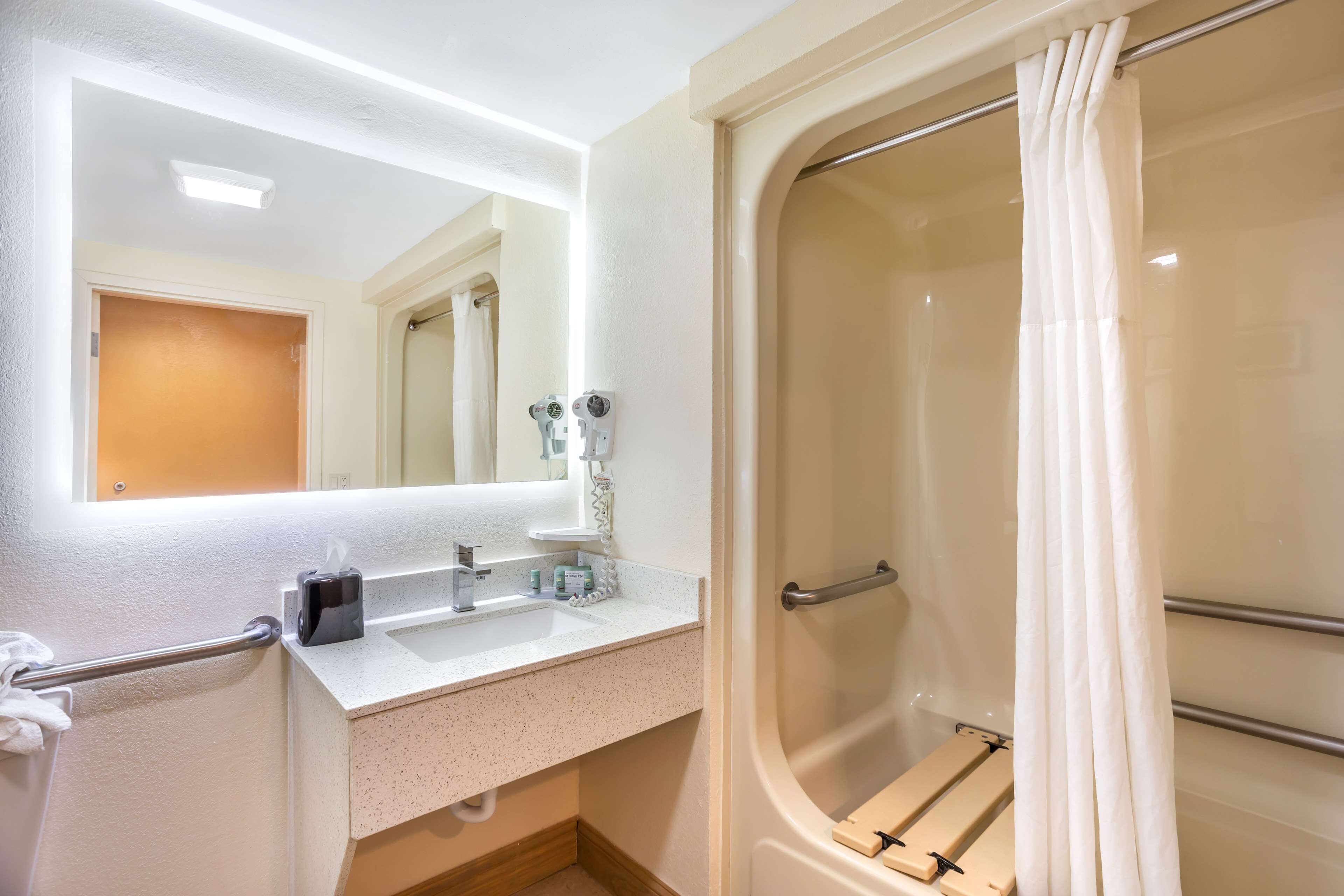 Un baño con lavamanos blanco, espejo y ducha.