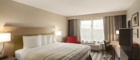 A hotel room with a bed, a desk, a chair, a TV, and a window with curtains.