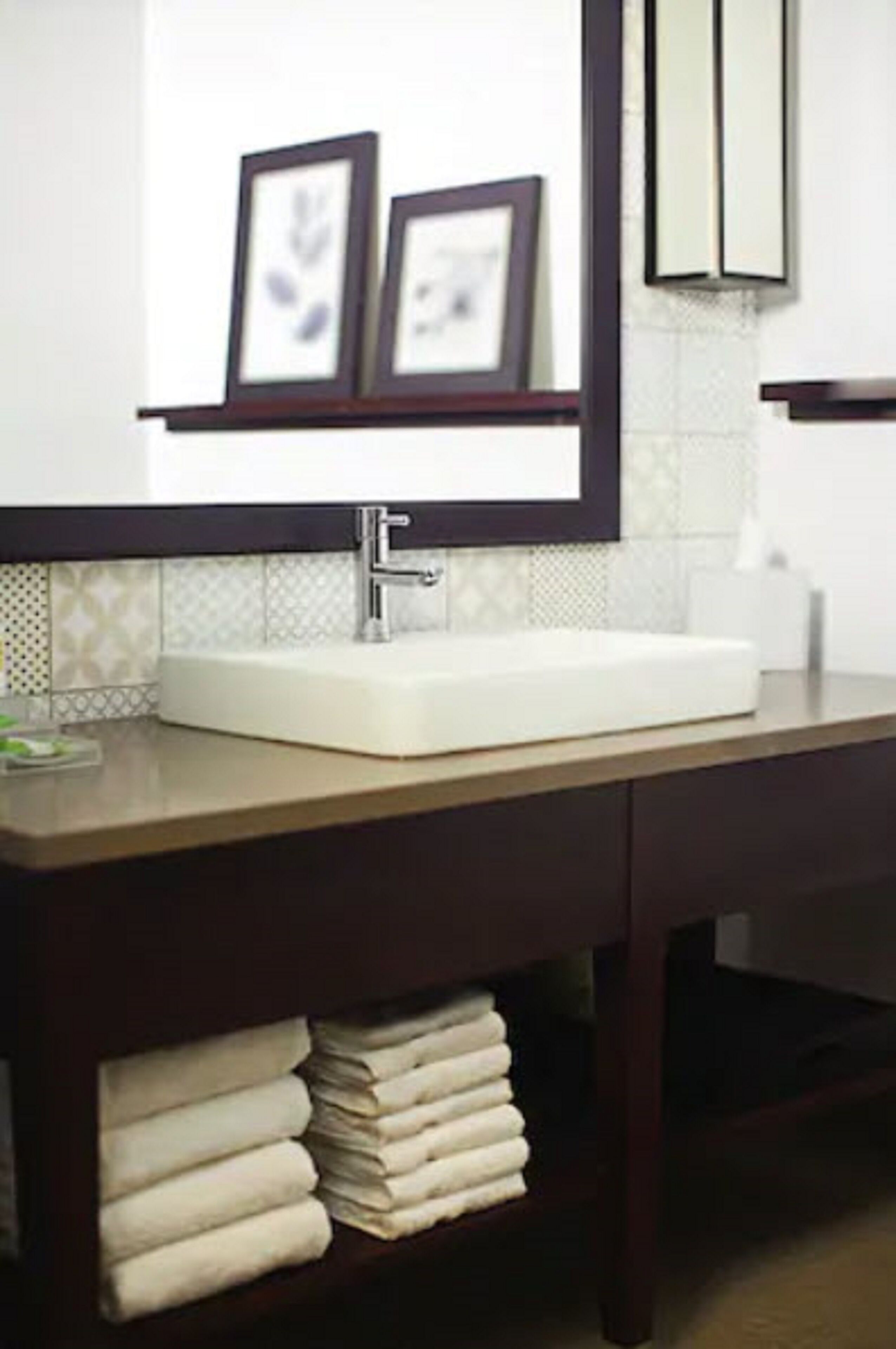A bathroom with a white sink, dark wooden vanity, and a mirror above the sink.