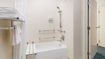 A bathroom with a white bathtub, a shower, and a towel rack.