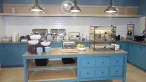 A kitchen with blue cabinets, a central island with a toaster, bowls, and a fruit bowl. There are two pendant lights above the island. - Country Inn & Suites by Radisson, Helen, GA (Helen)
