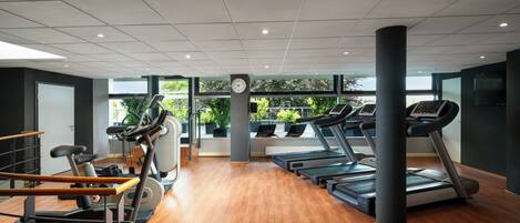 Een moderne sportschool met loopbanden, elliptische trainers en gewichten.