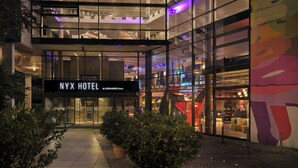 Le NYX HOTEL, un établissement du groupe LEONARDO Hotels, se distingue par sa façade moderne en verre, son entrée bien visible et une fresque colorée sur le côté droit.