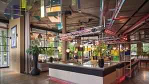 Un espace bar moderne doté d’un îlot central, de sièges et de plantes en pot.
