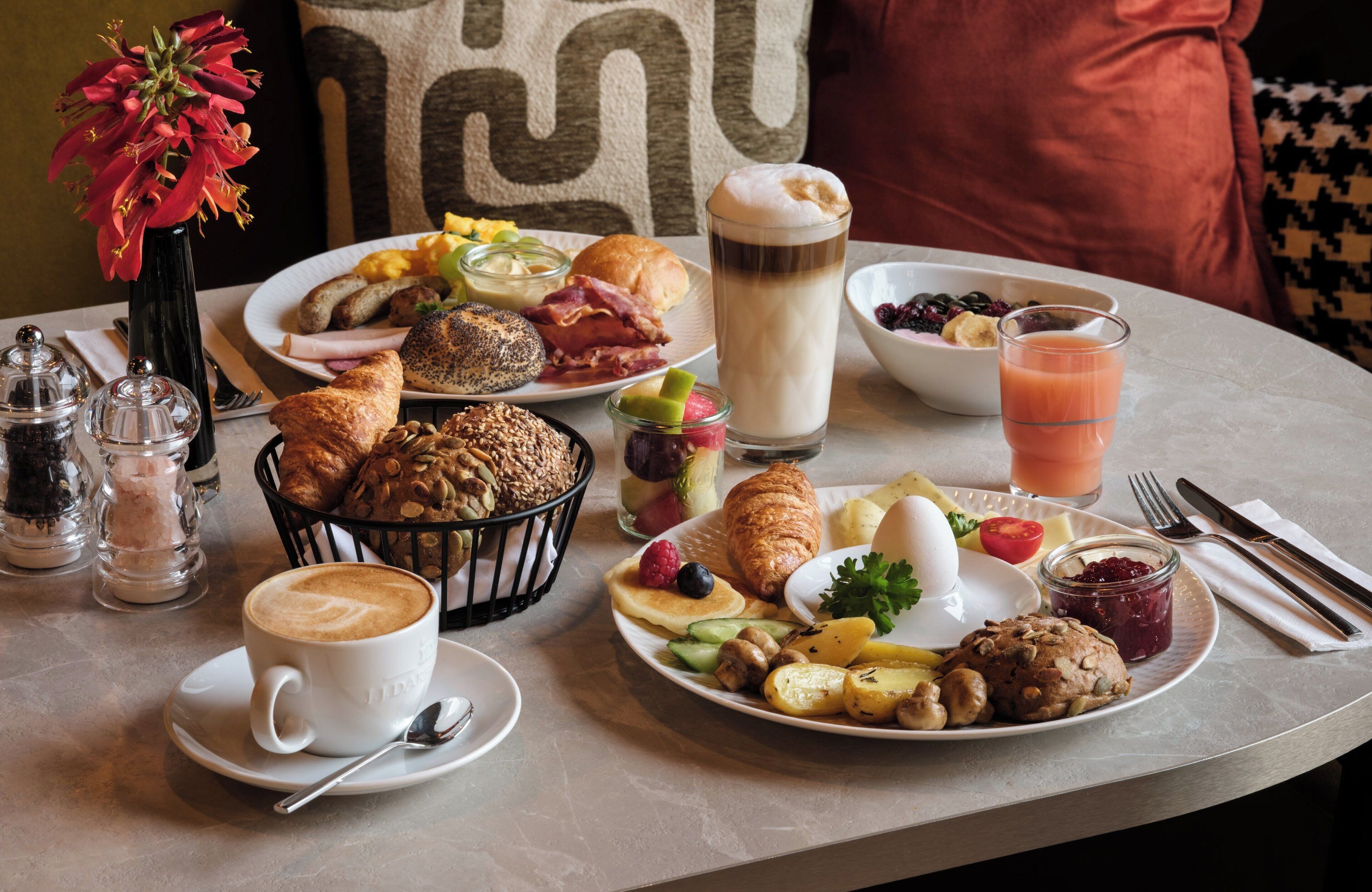 Een ontbijttafel met diverse etenswaren, een koffiekop en een glas sap.