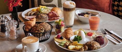 Een ontbijttafel met diverse etenswaren, een koffiekop en een glas sap.