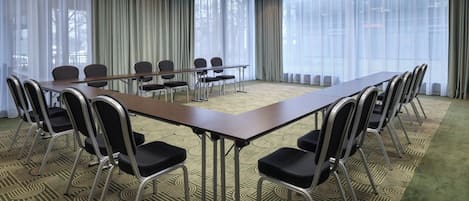 A conference room with a long table, chairs, and a carpeted floor.