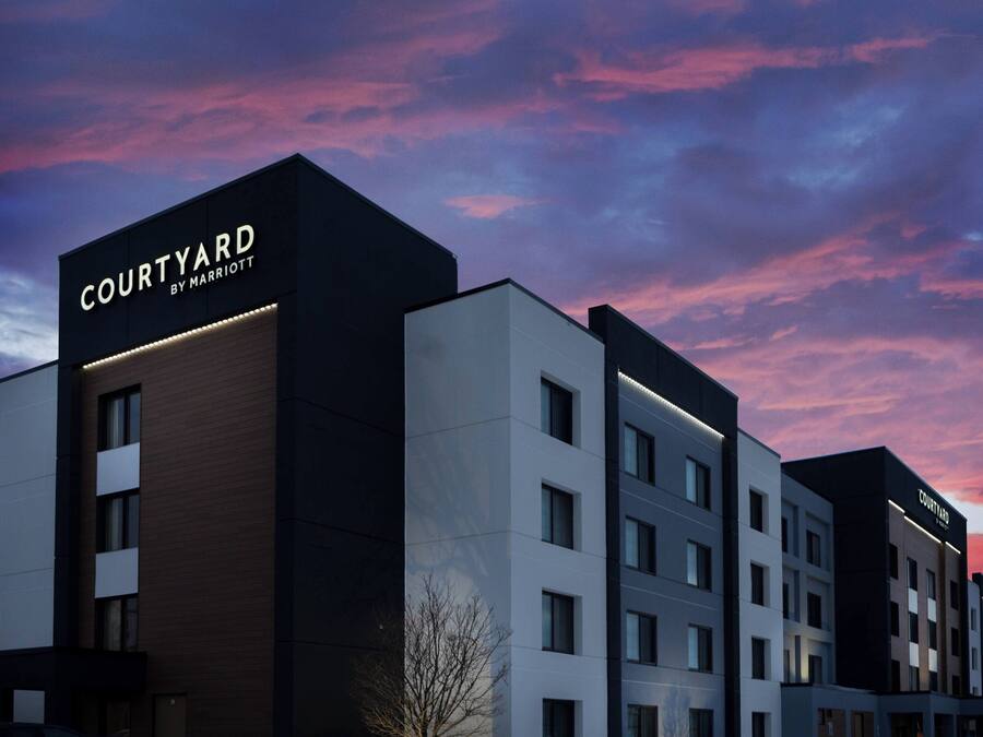 Un hotel Courtyard by Marriott con un diseño moderno, que cuenta con varios pisos y un letrero llamativo.