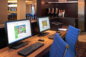 A hotel reception desk with two computer monitors, a keyboard, a mouse, and a blue chair.