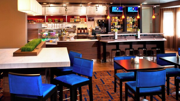 A restaurant with blue chairs, a bar area, and a television screen. - Courtyard by Marriott Cleveland Independence (Independence)