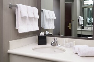 Un baño moderno con un espejo grande, dos toalleros, un lavabo y artículos de aseo.