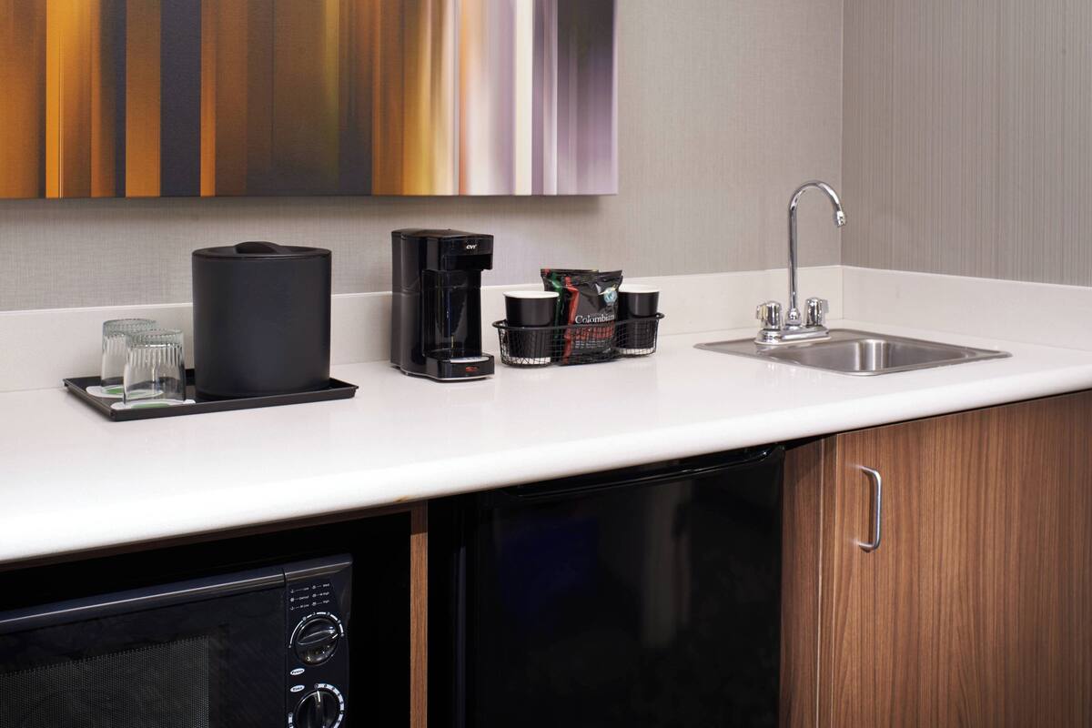 Cozinha moderna com cafeteira, xícaras de café e uma pia.