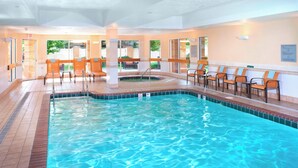 A swimming pool with clear blue water, surrounded by chairs and a sunlit interior. - Courtyard by Marriott Cleveland Independence (Independence)