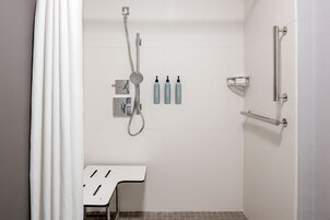 Un baño moderno con ducha, perchero y dispensador de jabón.