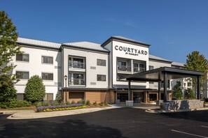 A Courtyard by Marriott hotel with a modern design, featuring a covered entrance and a landscaped front yard. - Courtyard by Marriott Ballantyne (Charlotte)