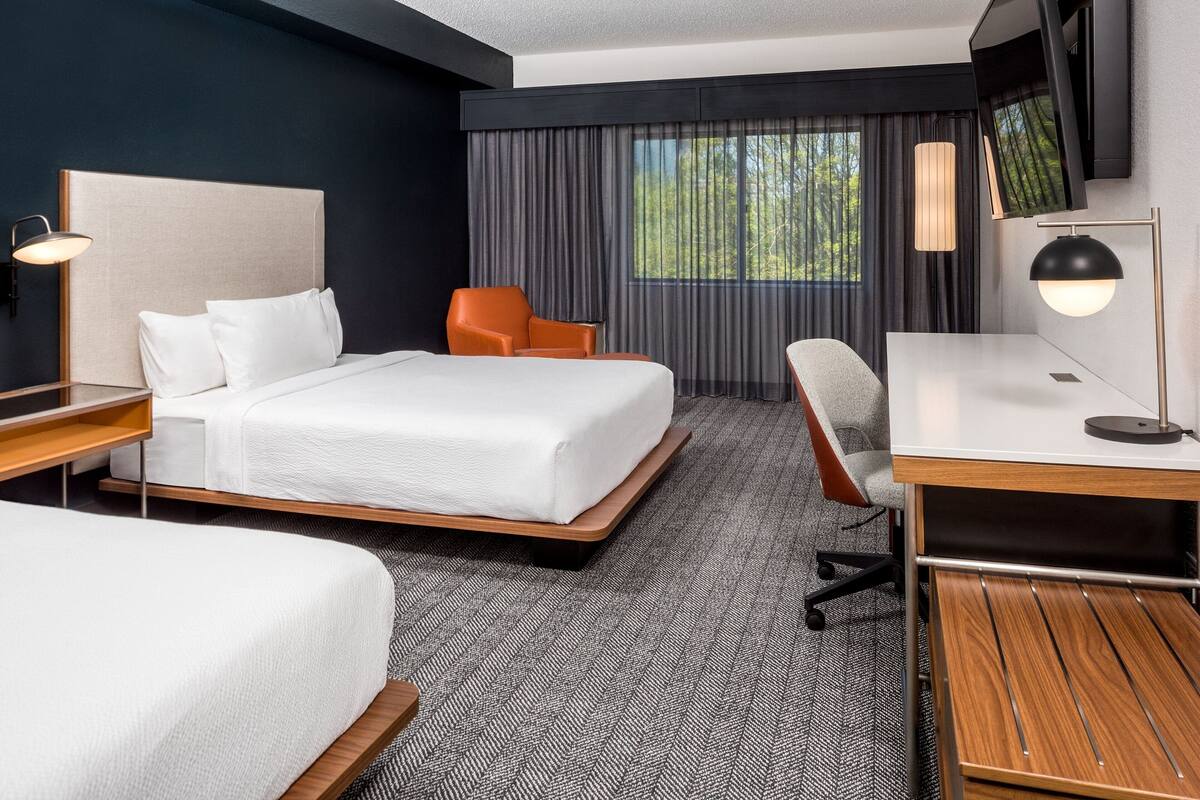 A hotel room with a large bed, a desk, a chair, and a TV mounted on the wall.