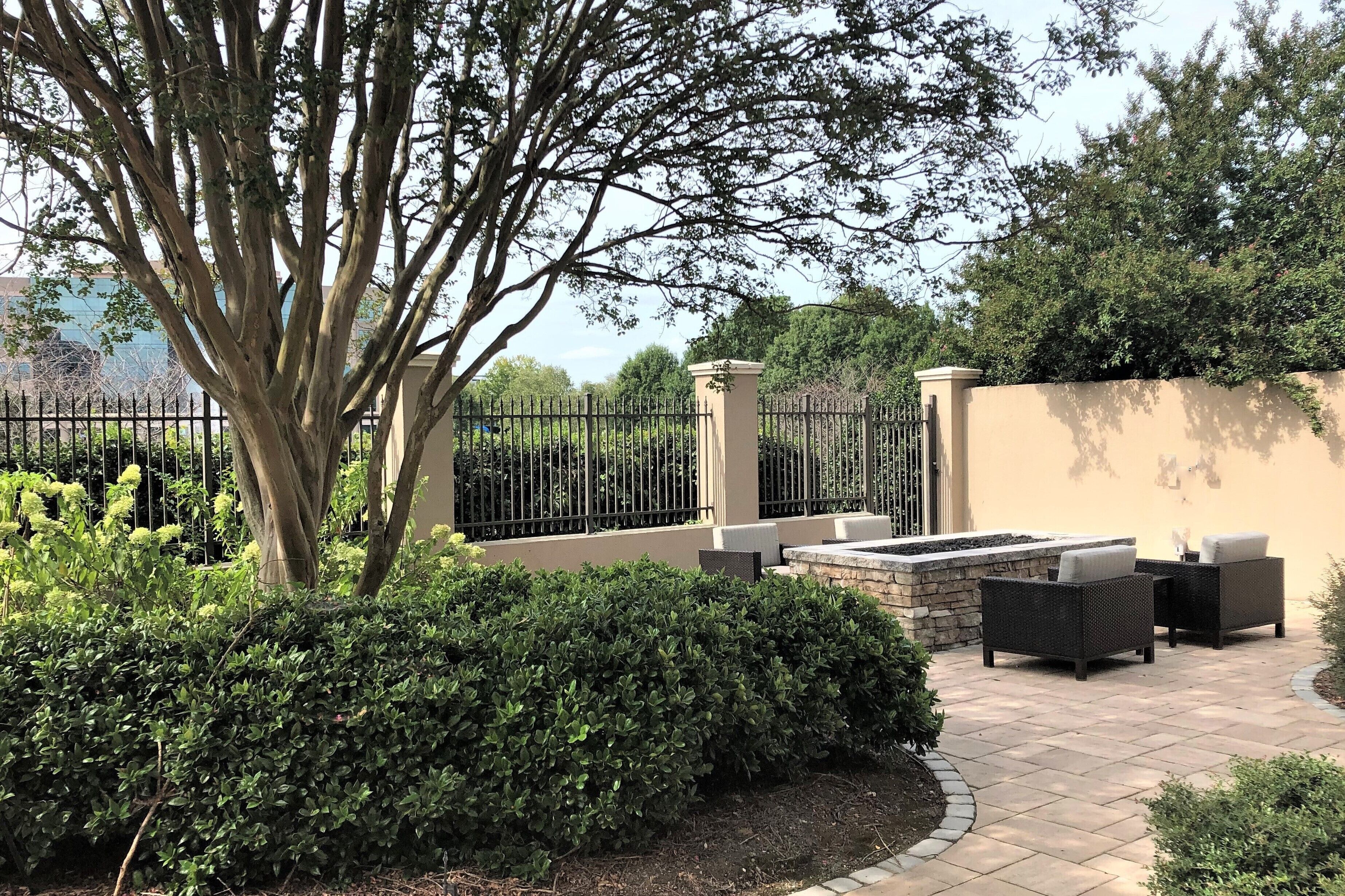A patio area with outdoor furniture, a stone wall, and a large tree.