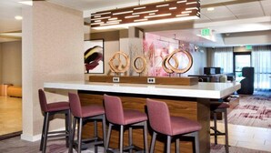 A bar area with a central island, bar stools, and a modern light fixture. - Courtyard by Marriott Ballantyne (Charlotte)