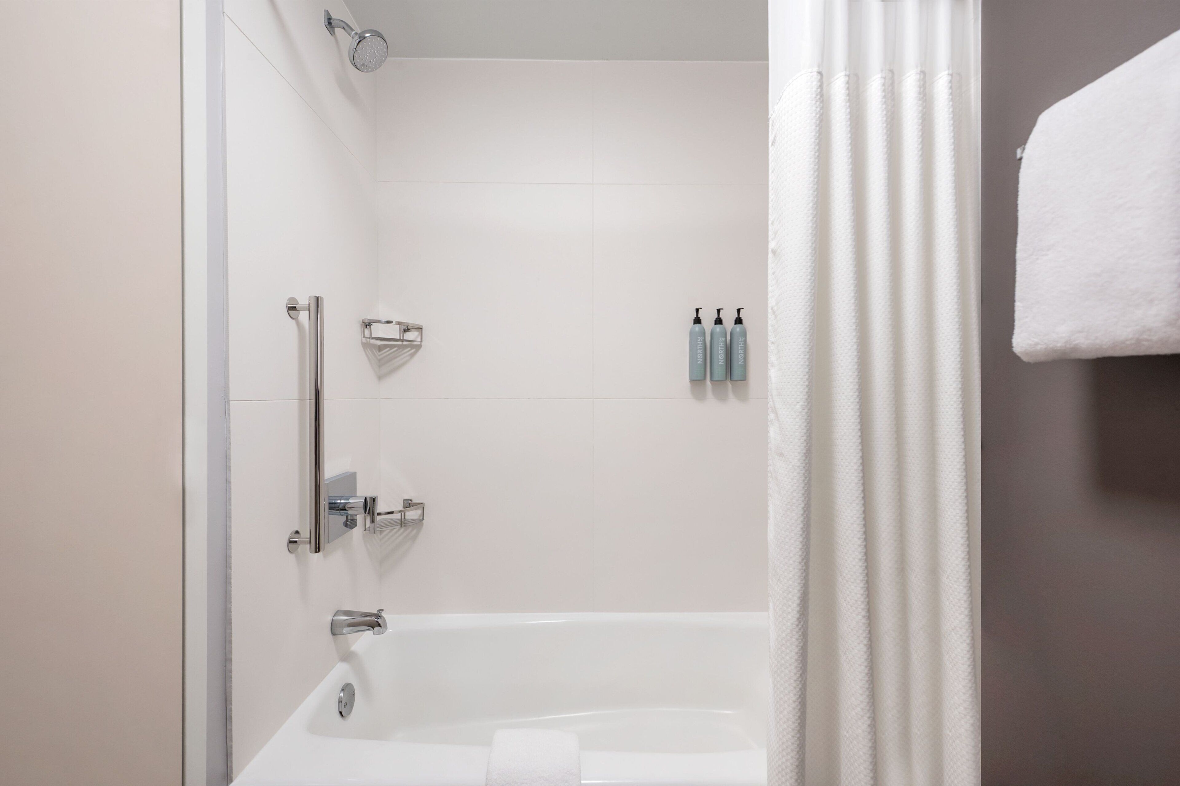 Un baño moderno con una bañera blanca, zona de ducha y un perchero para toallas.