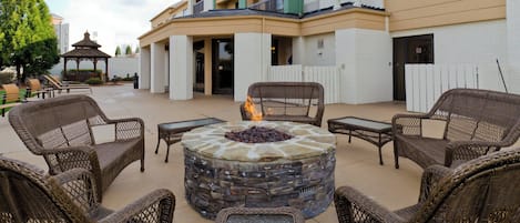 An outdoor seating area with wicker chairs and a stone fire pit.