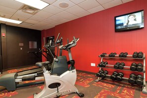 Ein Fitnessstudio mit Cardiogeräten, Laufbändern, Crosstrainern und einer Hantelbank.