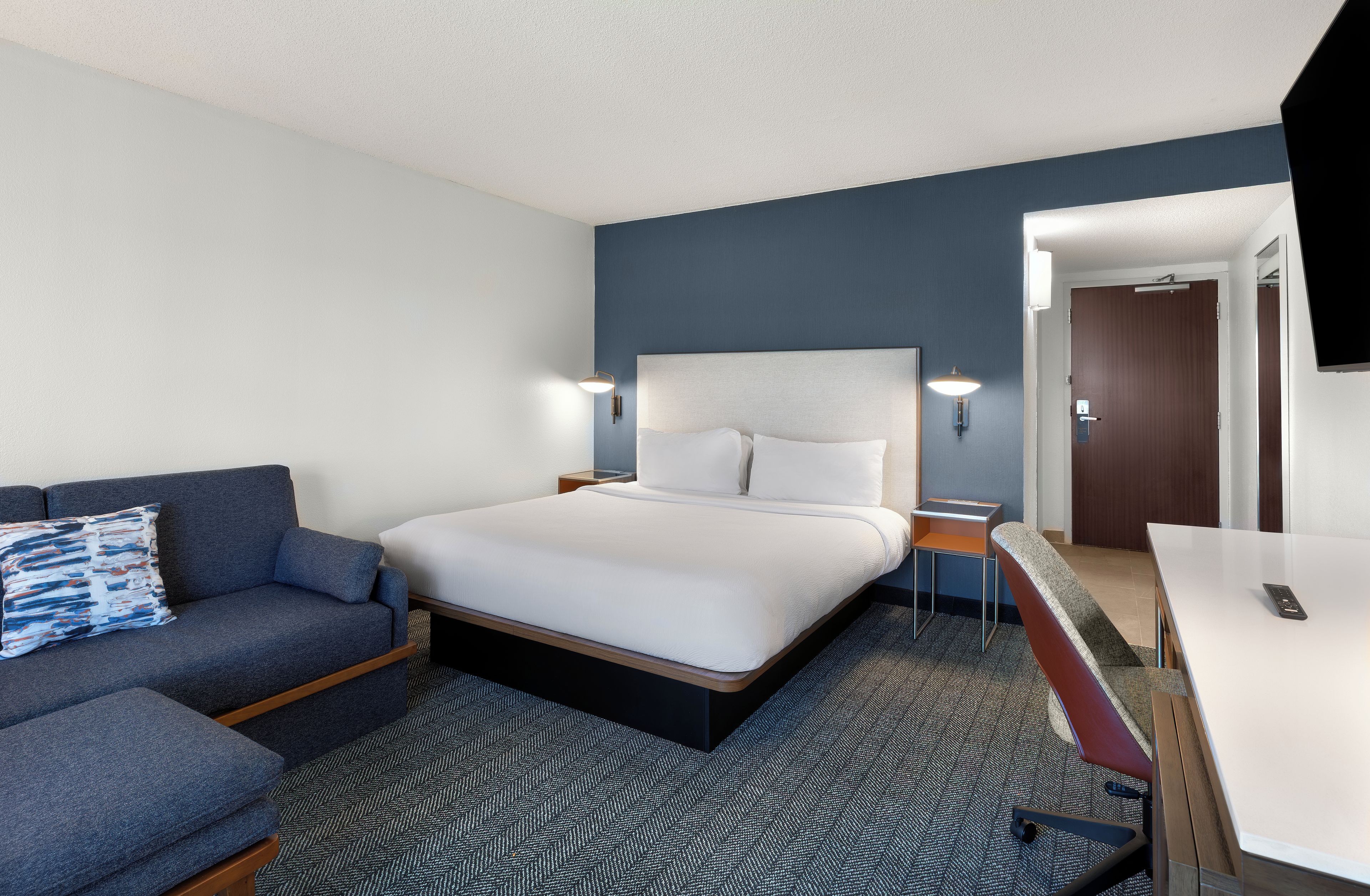 Une chambre d’hôtel avec un lit, un canapé, un bureau et une télévision.