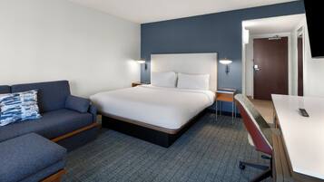 Une chambre d’hôtel avec un lit, un canapé, un bureau et une télévision.