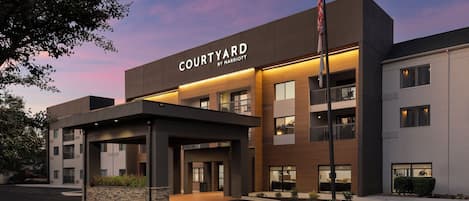 A Courtyard by Marriott hotel with a modern design, featuring a covered entrance and a parking lot.