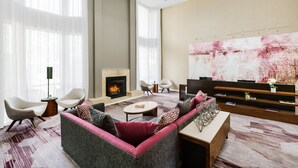 A modern living room with a fireplace, comfortable seating, and a large abstract painting on the wall. - Courtyard By Marriott Dallas - Lewisville (Lewisville)