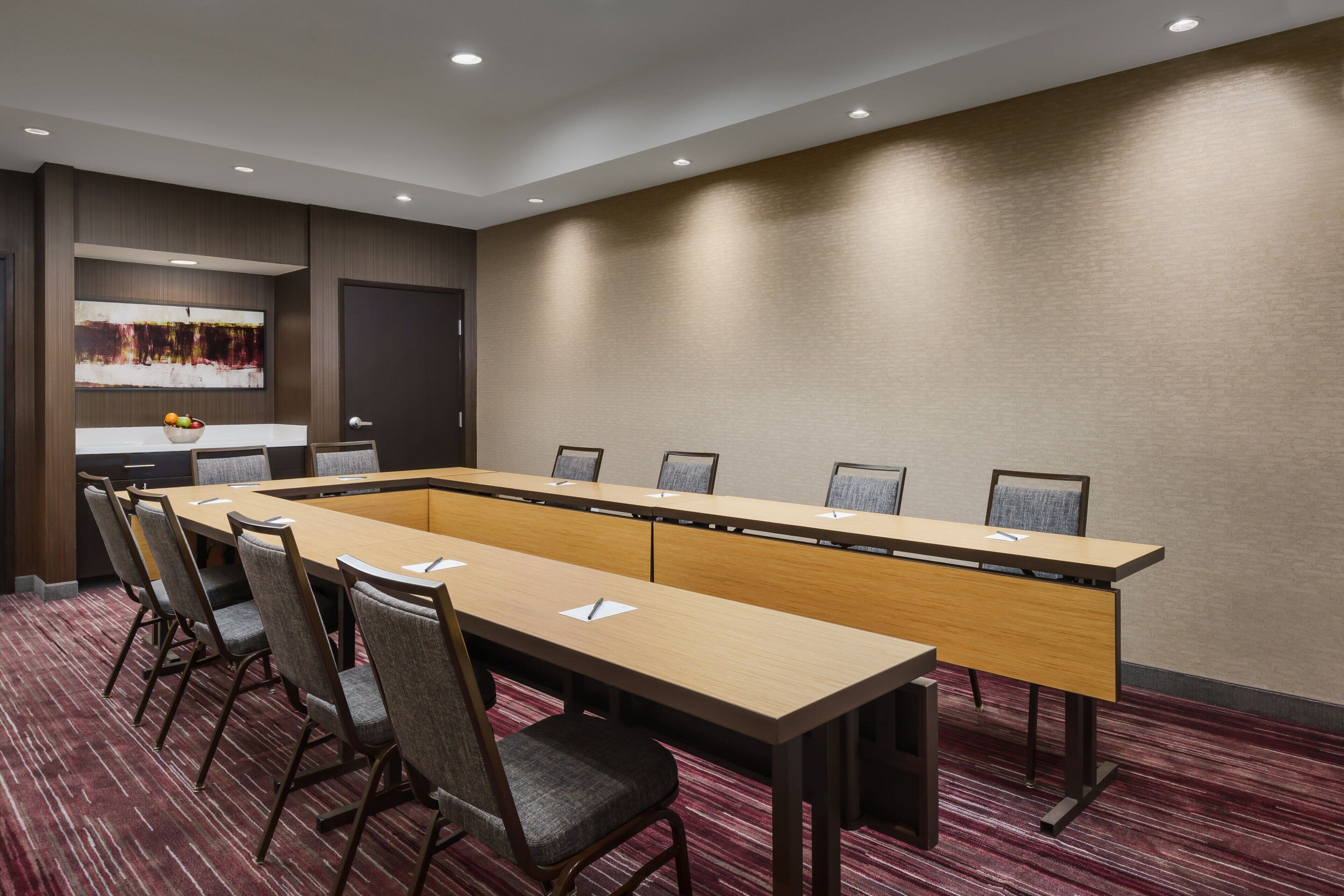 A conference room with a long table, six chairs, and a large window.
