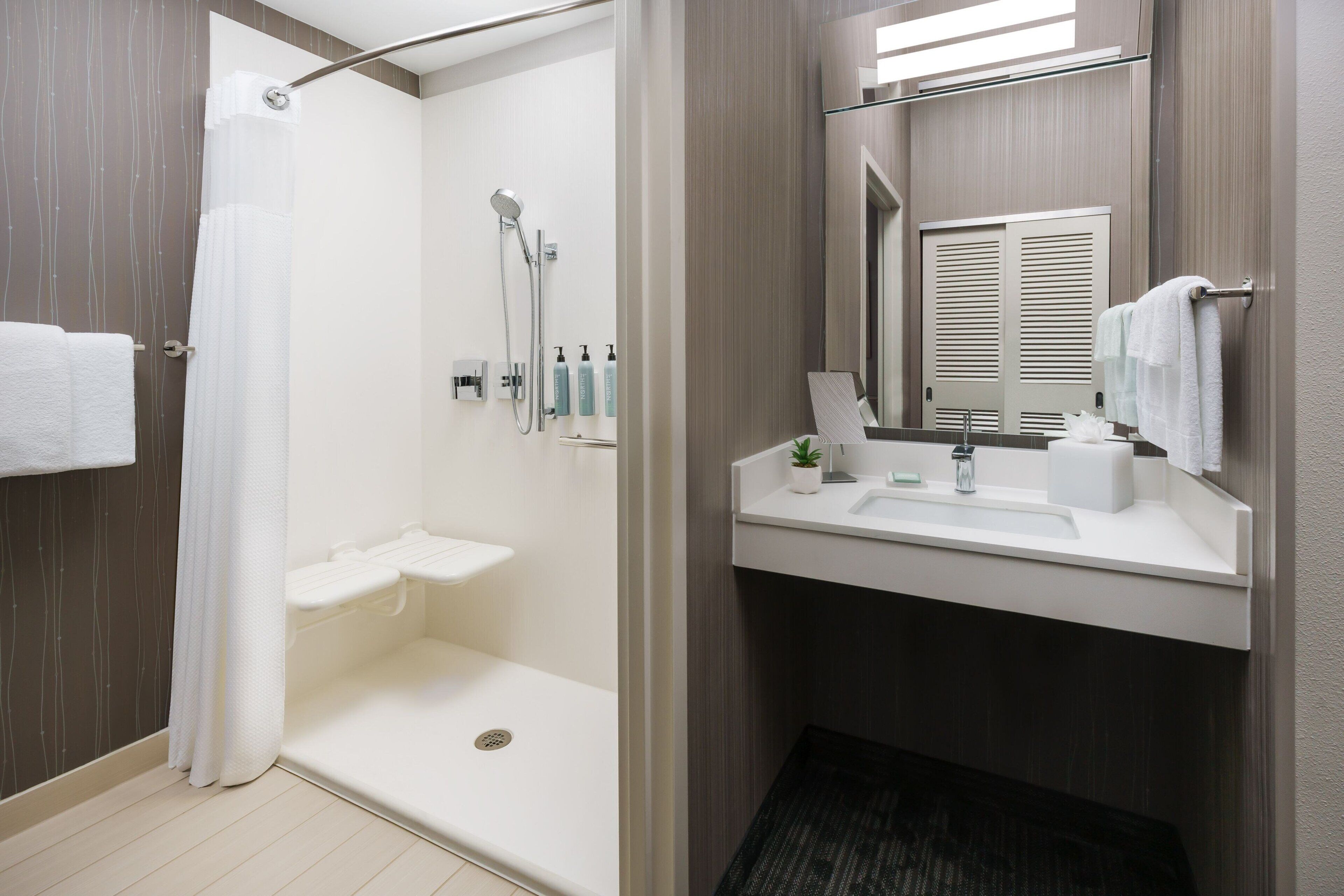 Un baño moderno con ducha, inodoro, lavabo y espejo.