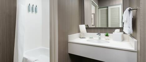 A modern bathroom with a bathtub, a sink with a mirror, and toiletries on the wall.