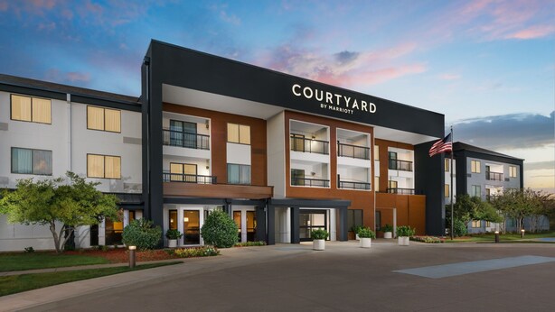 A Courtyard by Marriott hotel with a modern design, multiple balconies, and a well-maintained outdoor area. - Courtyard By Marriott Dallas - Lewisville (Lewisville)