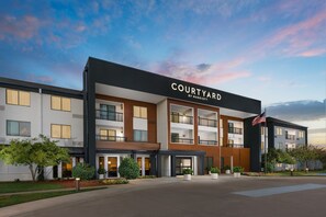 A Courtyard by Marriott hotel with a modern design, multiple balconies, and a well-maintained outdoor area.
