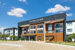Un hotel Courtyard by Marriott con diseño moderno, varios balcones y una bandera.