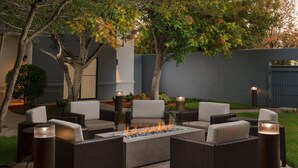An outdoor seating area with wicker furniture and a central fire feature. - Courtyard By Marriott Dallas - Lewisville (Lewisville)