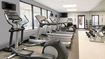 A gym with treadmills, elliptical machines, and dumbbells.