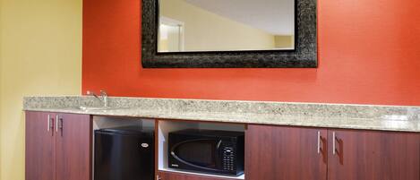 A kitchen with a microwave, dishwasher, and a sink under a mirror.