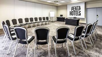 A conference room with a large screen displaying "PENTA HOTELS" and a reception desk.