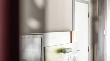 Una moderna camera d'albergo con TV a schermo piatto, un comodino, una sedia e una porta.
