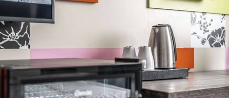 Una zona de cocina con microondas, hervidor y cafetera sobre la encimera.